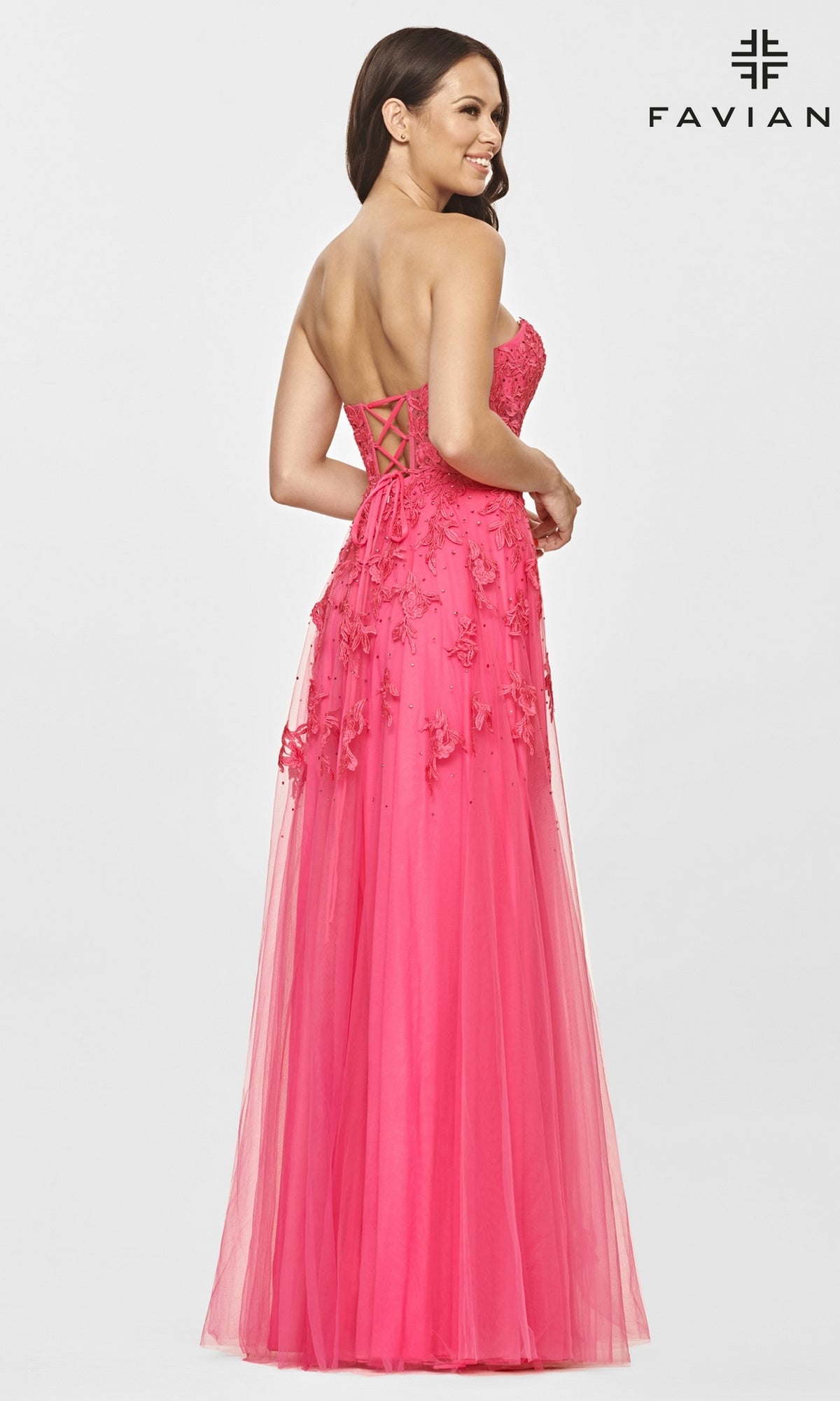 Woman in a Faviana Strapless Sweetheart Long Lace Prom Dress, bright pink with floral appliqué and lace-up back, stands against a plain white background.